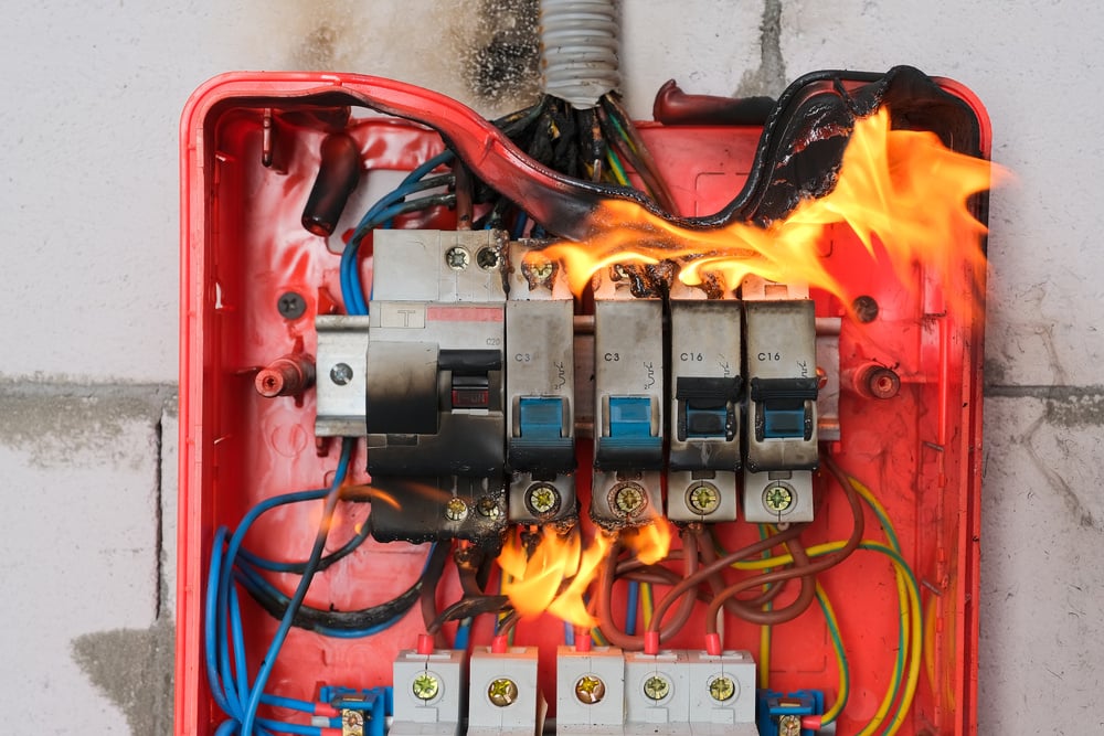 Burning switchboard from overload or short circuit on wall closeup